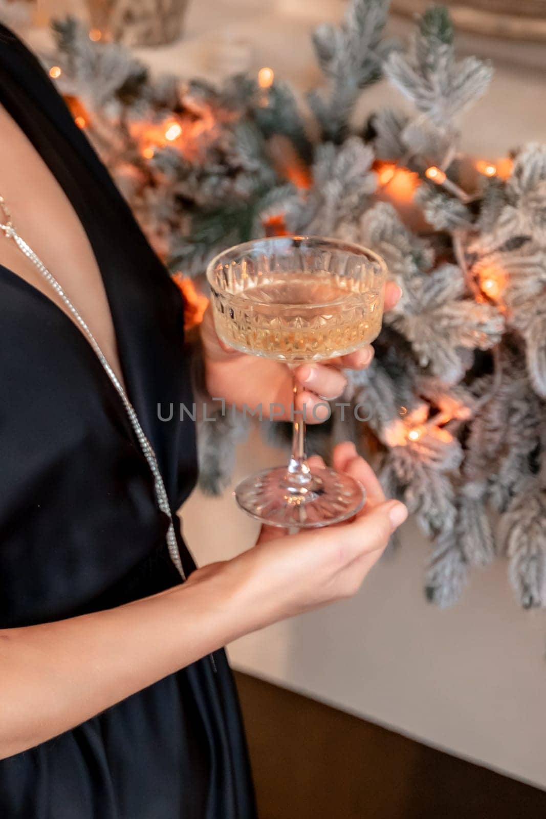 Portrait of a wealthy mature woman with evening make-up and hairstyle posing in a black dress on the background of the Christmas room. Luxurious lifestyle. Christmas holidays concept by Matiunina