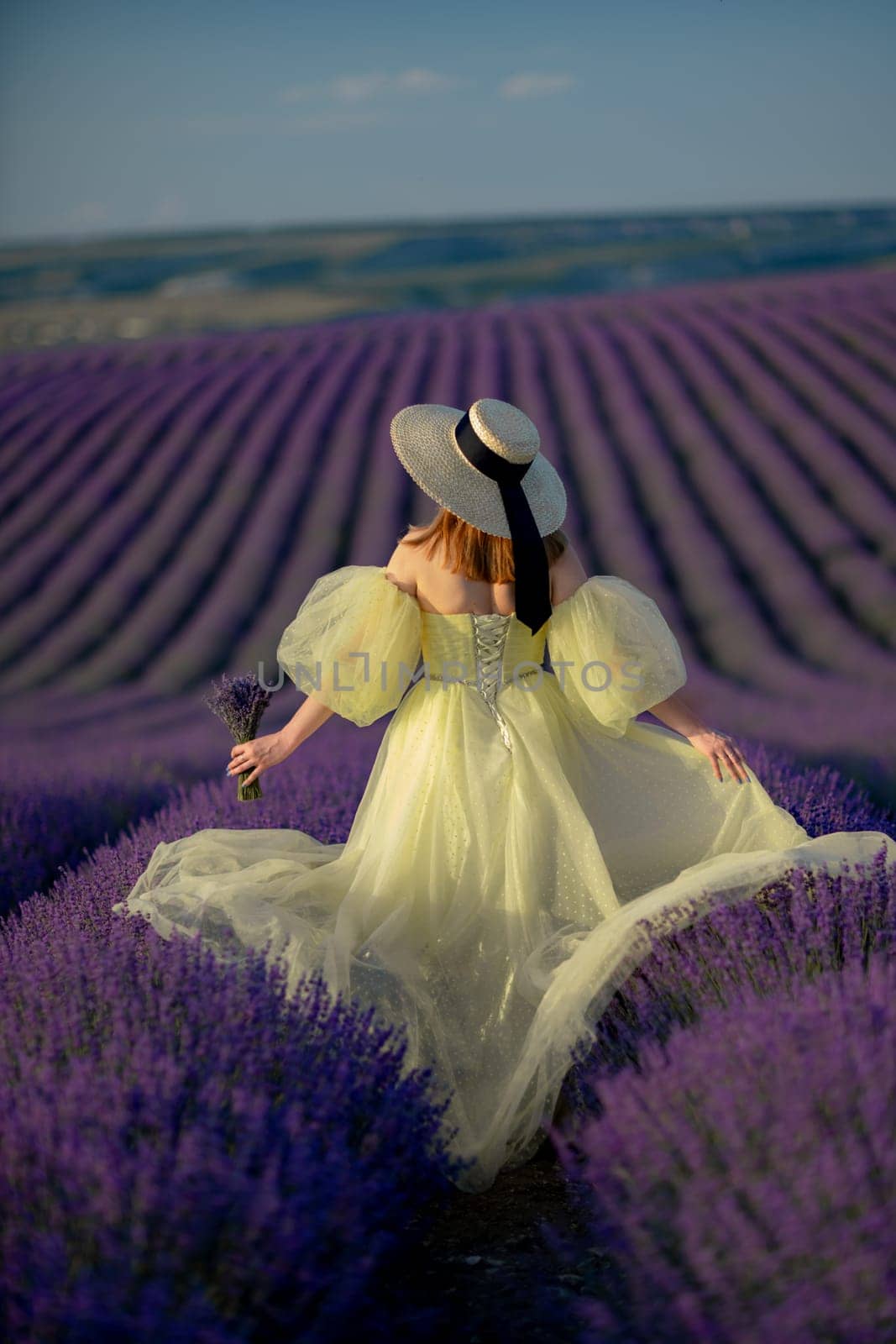 Back view woman lavender sunset. Happy woman in yellow dress holds lavender bouquet. Aromatherapy concept, lavender oil, photo session in lavender by Matiunina