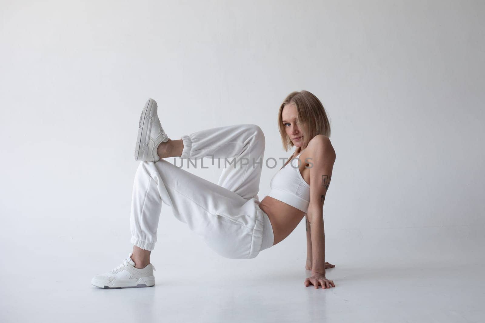 Beautiful blonde girl in a white top and tights posing on a white background by Freeman_Studio