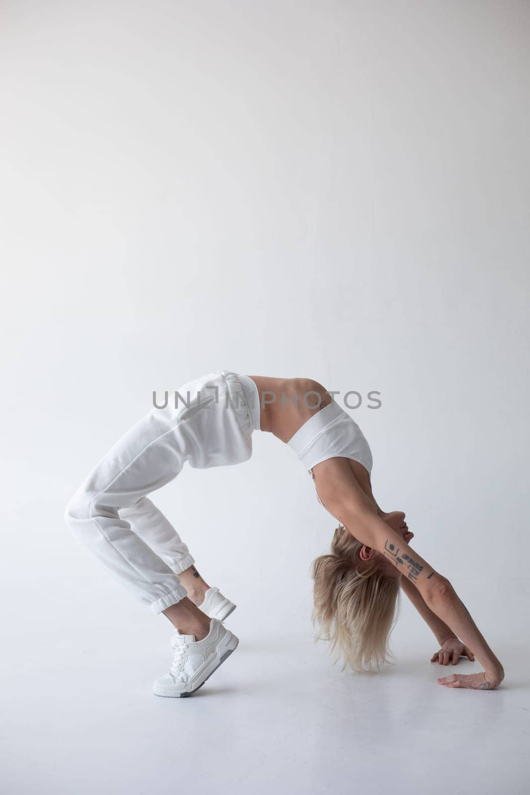 Beautiful blonde girl in a white top and tights posing on a white background. High quality photo