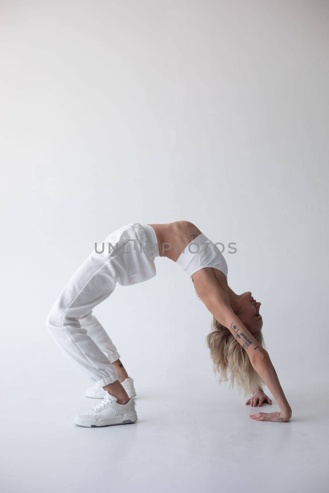 Beautiful blonde girl in a white top and tights posing on a white background. High quality photo