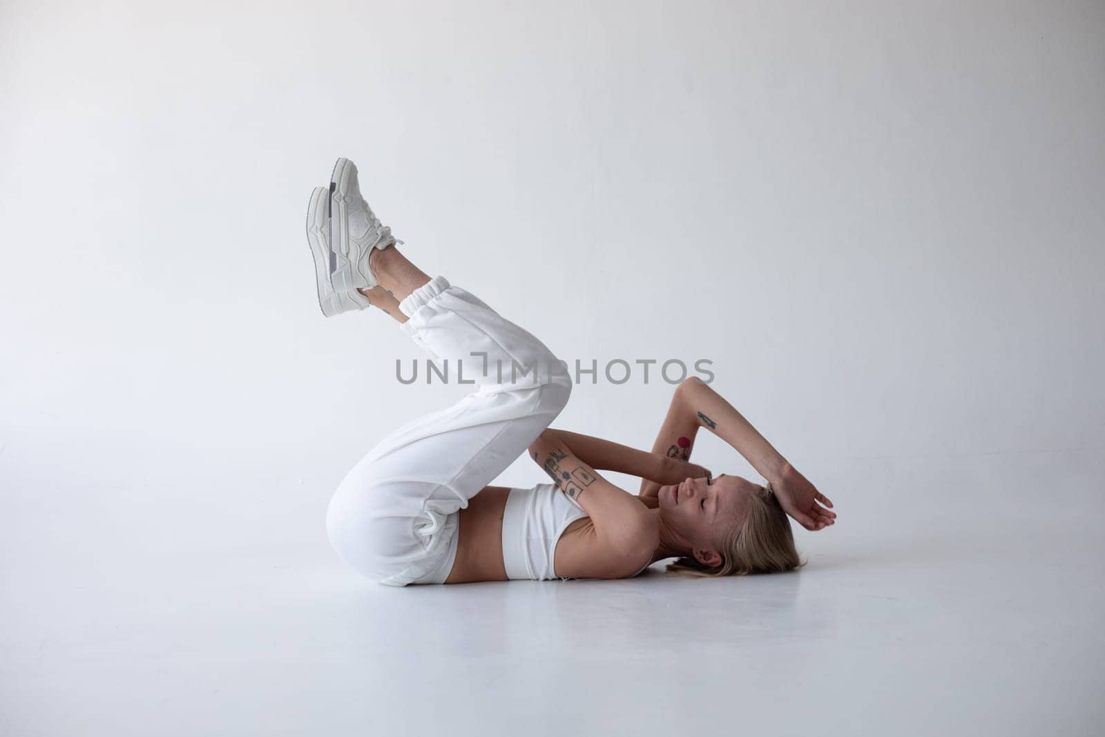 Beautiful blonde girl in a white top and tights posing on a white background. High quality photo