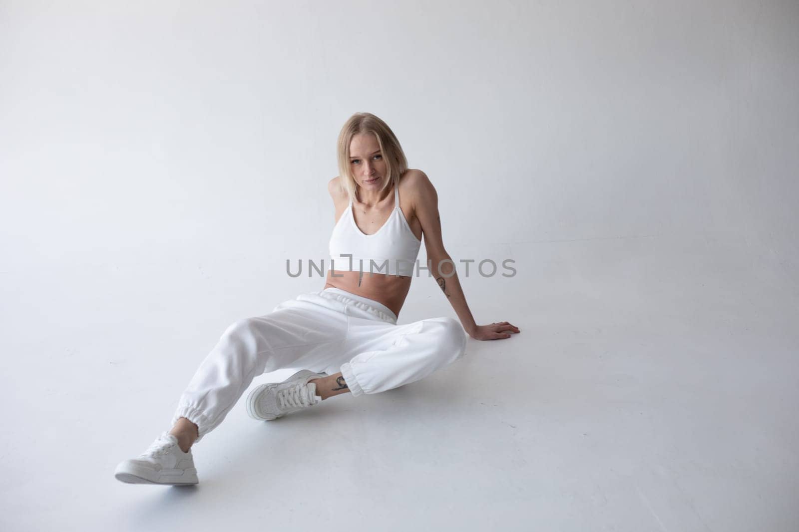 Beautiful blonde girl in a white top and tights posing on a white background. High quality photo