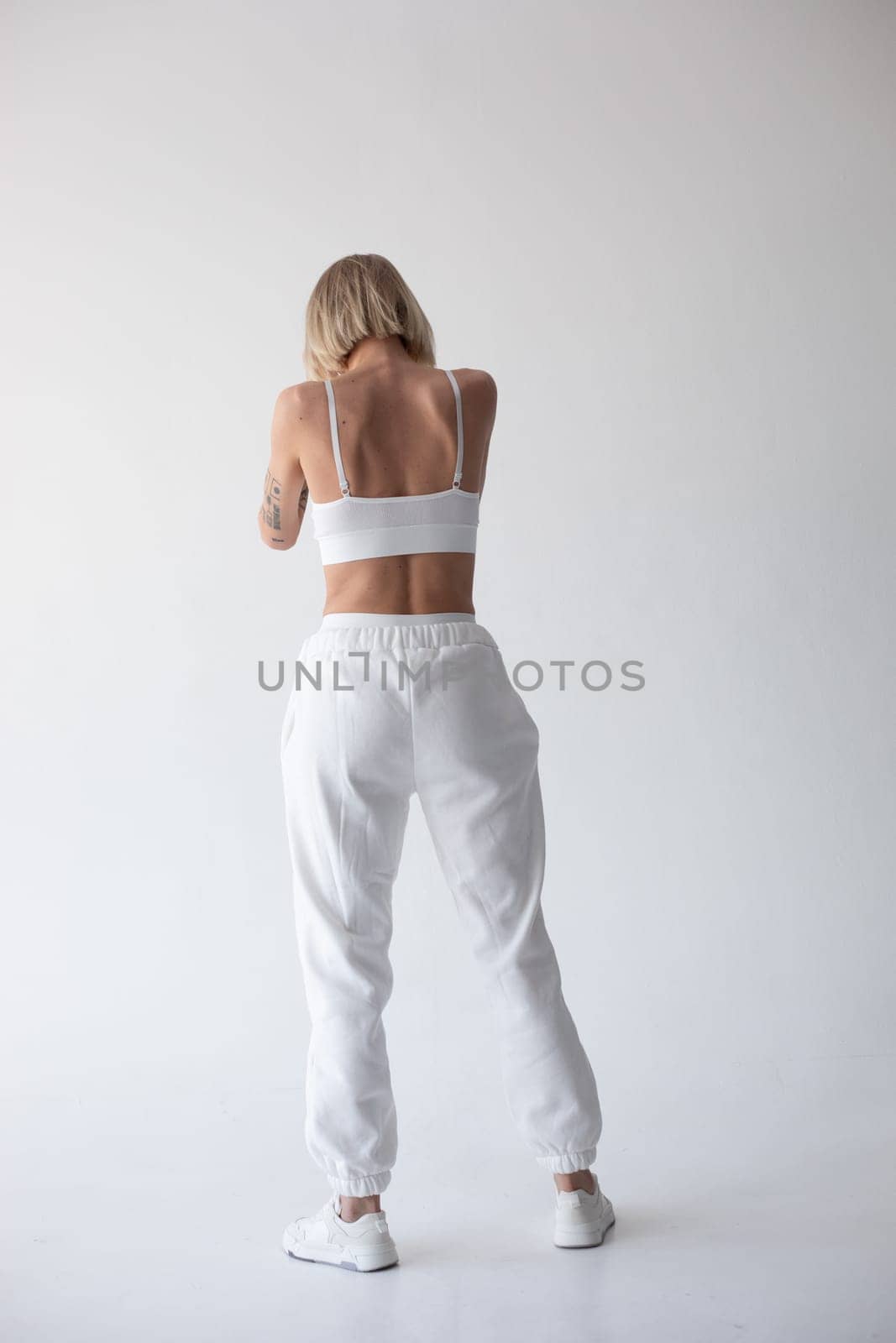 Beautiful blonde girl in a white top and tights posing on a white background by Freeman_Studio