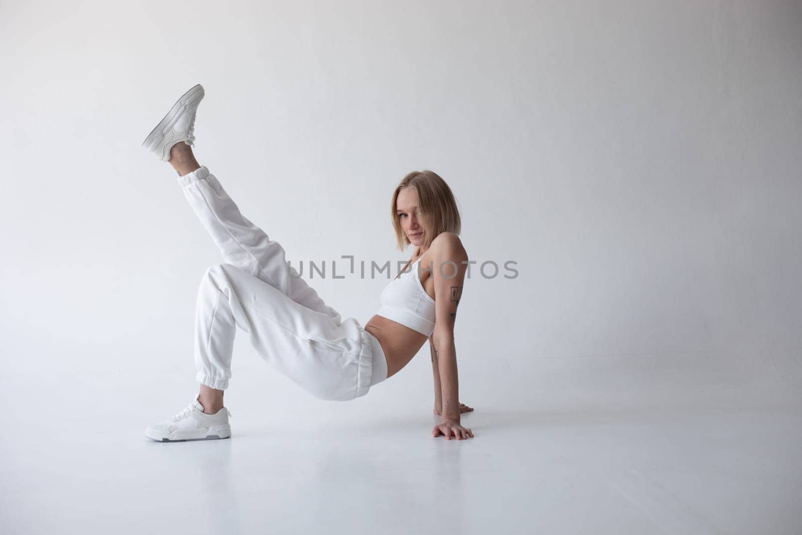 Beautiful blonde girl in a white top and tights posing on a white background. High quality photo