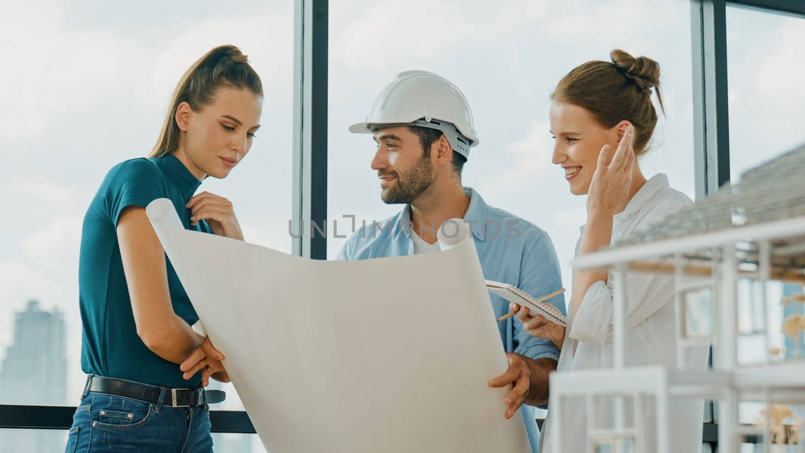 Professional architect engineer team talking, sharing, brainstorming about design while manager hold at project plan. Young architect holding plan while manager listen and point at plan. Tracery