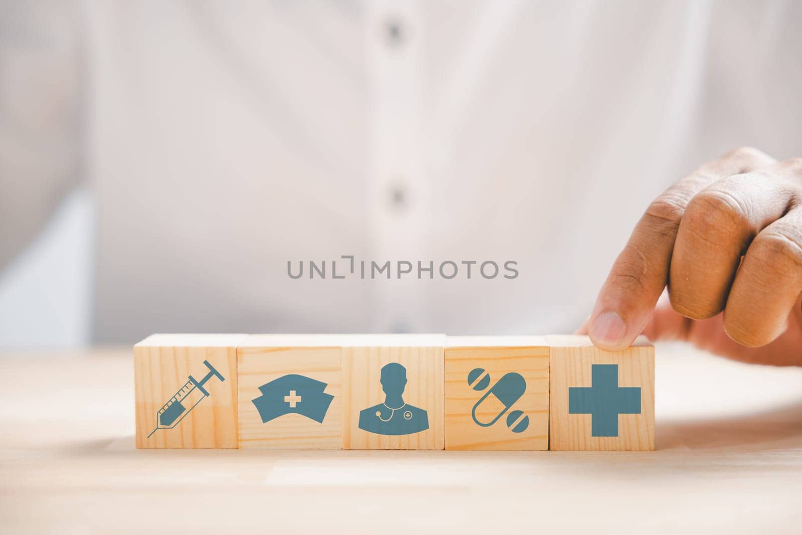 Wooden block held by hand showcases healthcare and medical icons. Portrays safety, health, and family well-being, symbolizing pharmacy, heart care, and happiness. health care concept