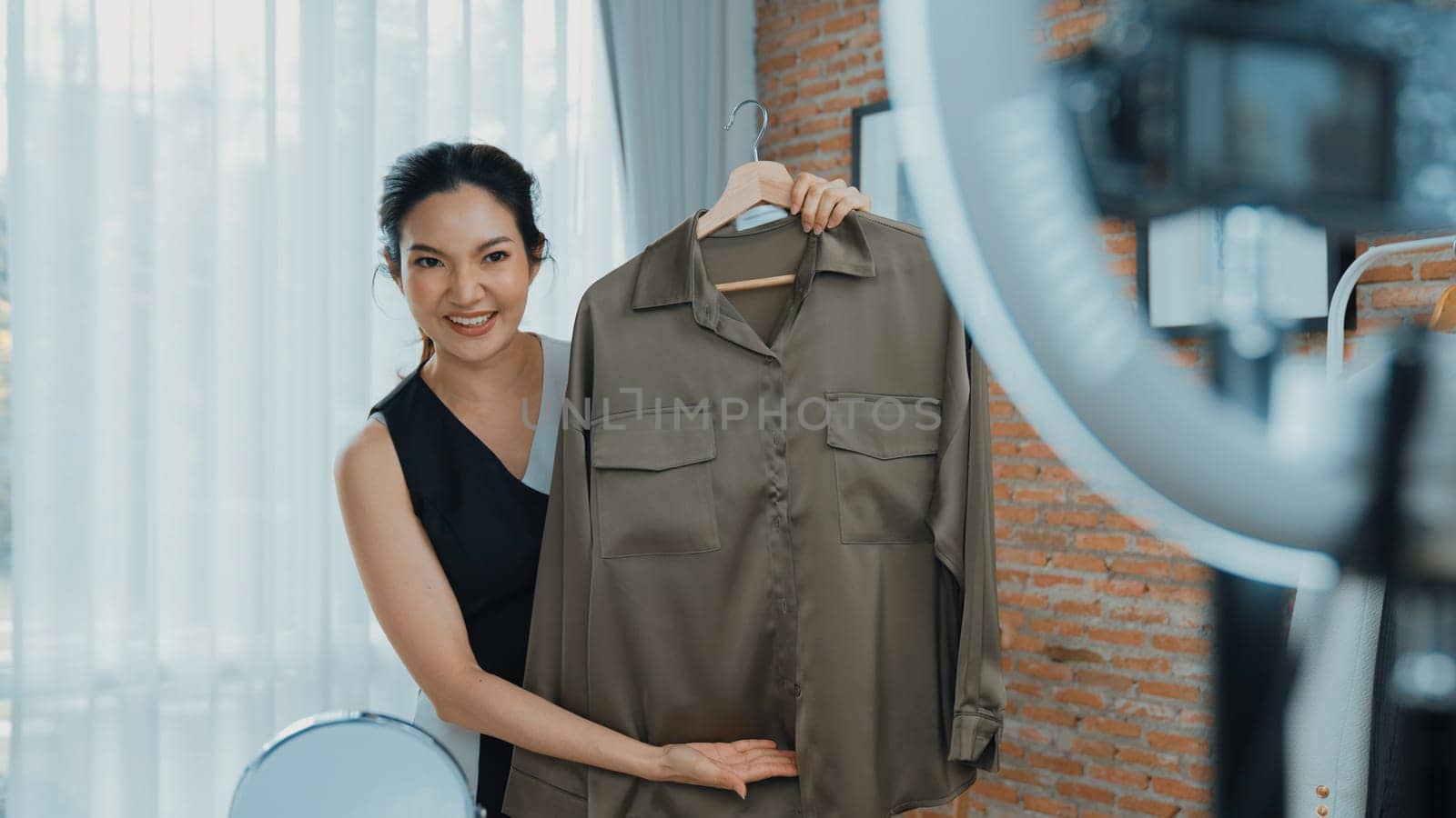 Woman influencer shoot live streaming vlog video review clothes social media or blog. Happy young girl with apparel vivancy studio lighting for marketing recording session broadcasting online.