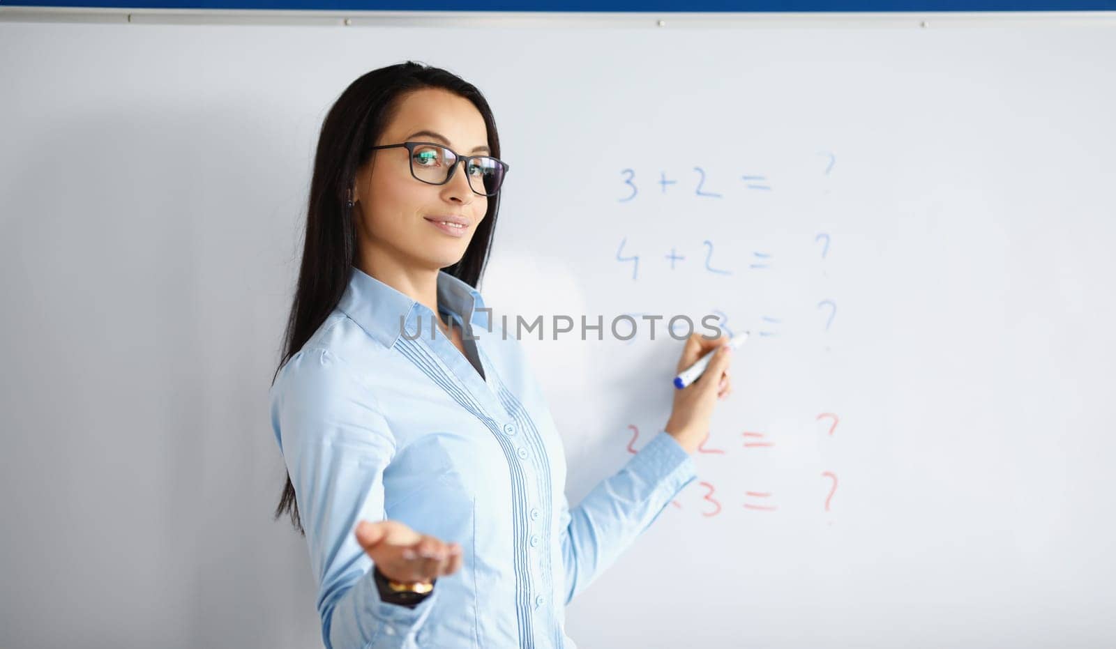 Woman teacher standing at blackboard with formulas and explaining information by kuprevich