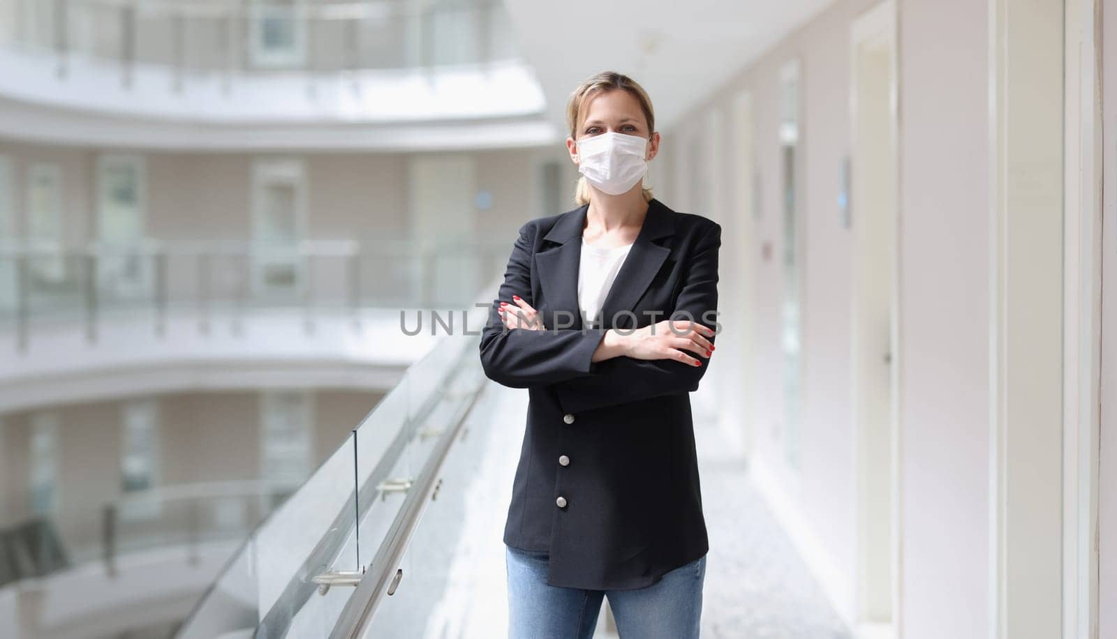 Young woman in suit and protective medical mask standing in corridor of hotel. Hotel customer service during covid19 pandemic concept