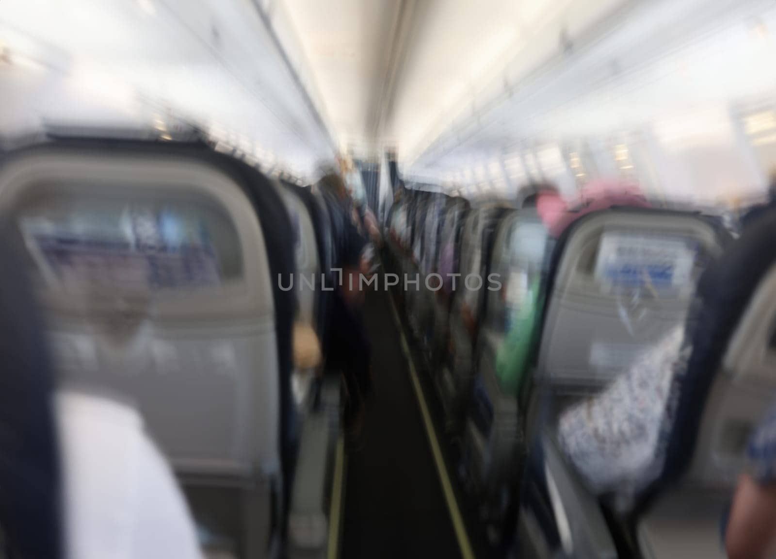 Passengers flying in aircraft cabin back view blurred background. Airplane turbulence concept