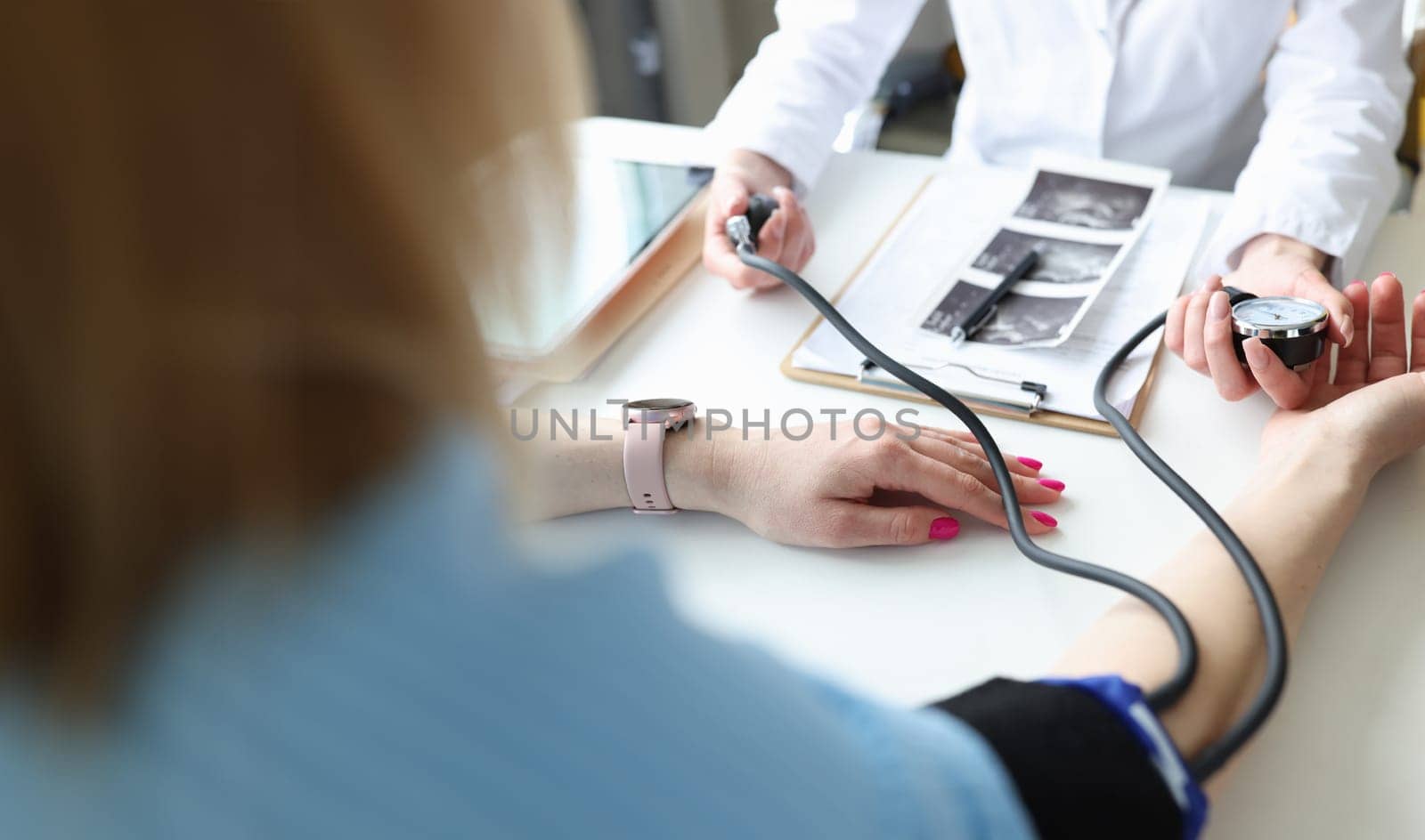 Gynecologist doctor measuring blood pressure of young pregnant woman in clinic closeup by kuprevich