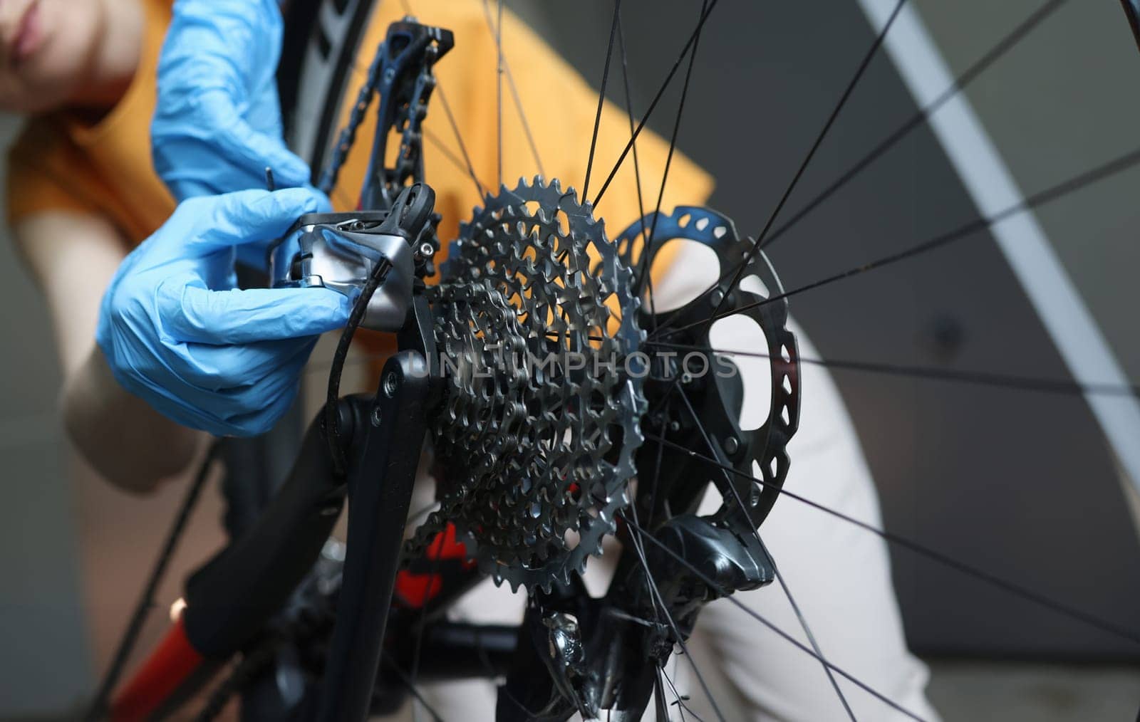 Craftsman in rubber protective gloves repairing bicycle closeup. Bicycle service concept
