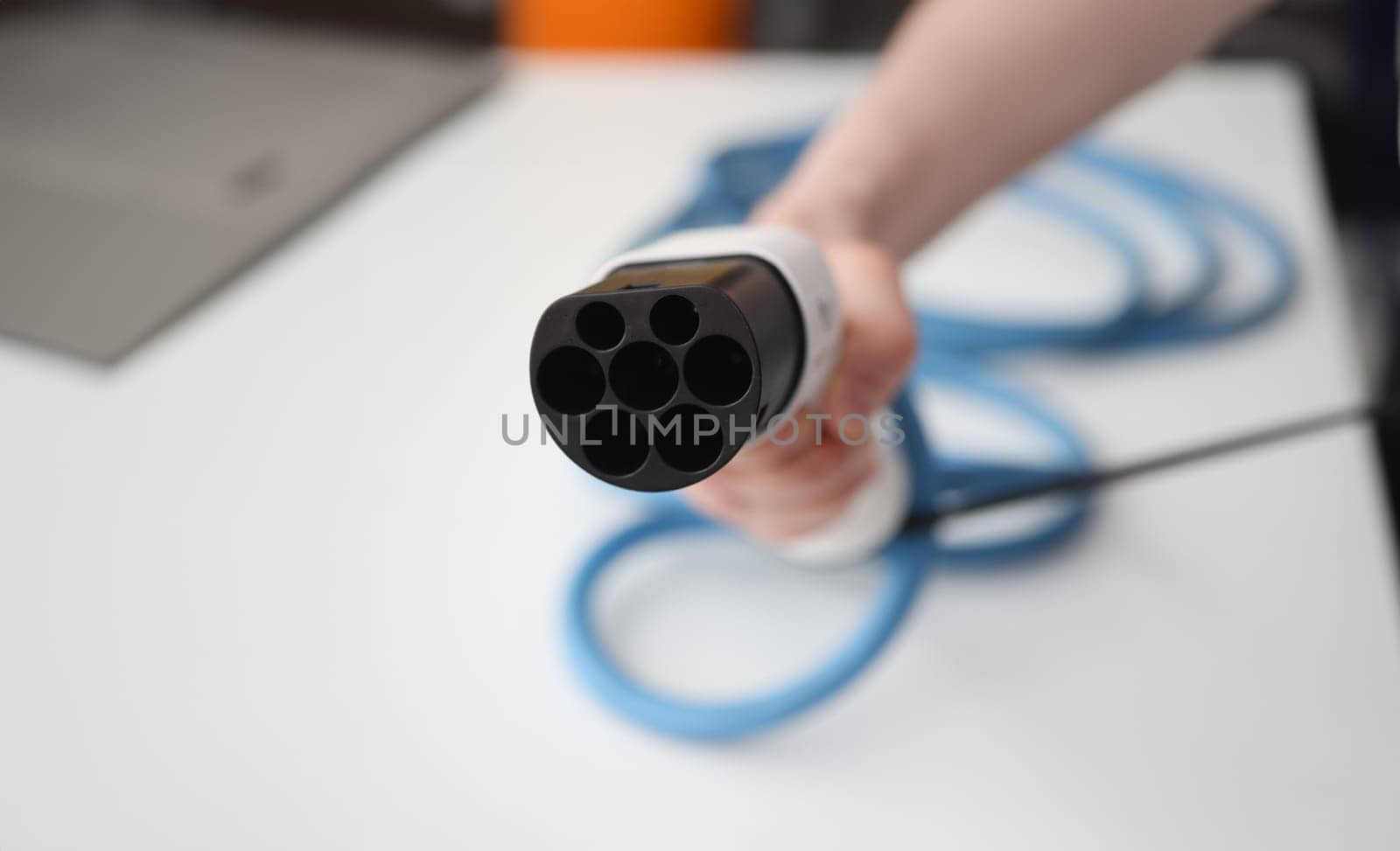 Man holding cable for electric cars in his hands closeup. Favorable transport concept