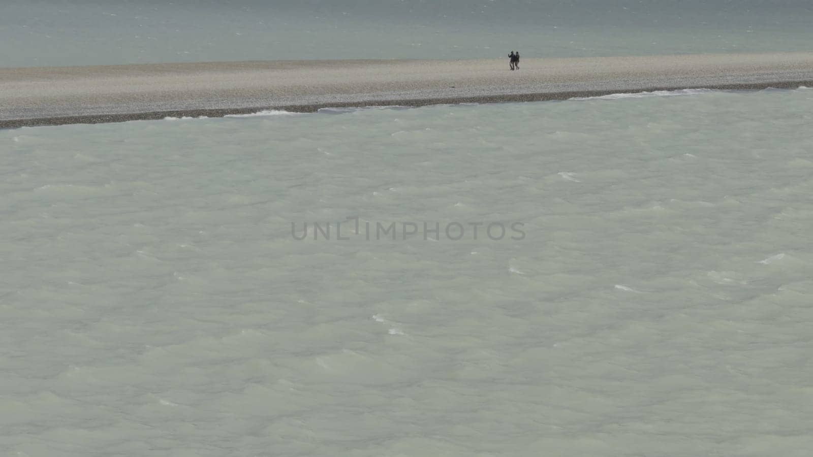 Couple Walking on Narrow Sand Strip Beside Glacial Waters by FerradalFCG
