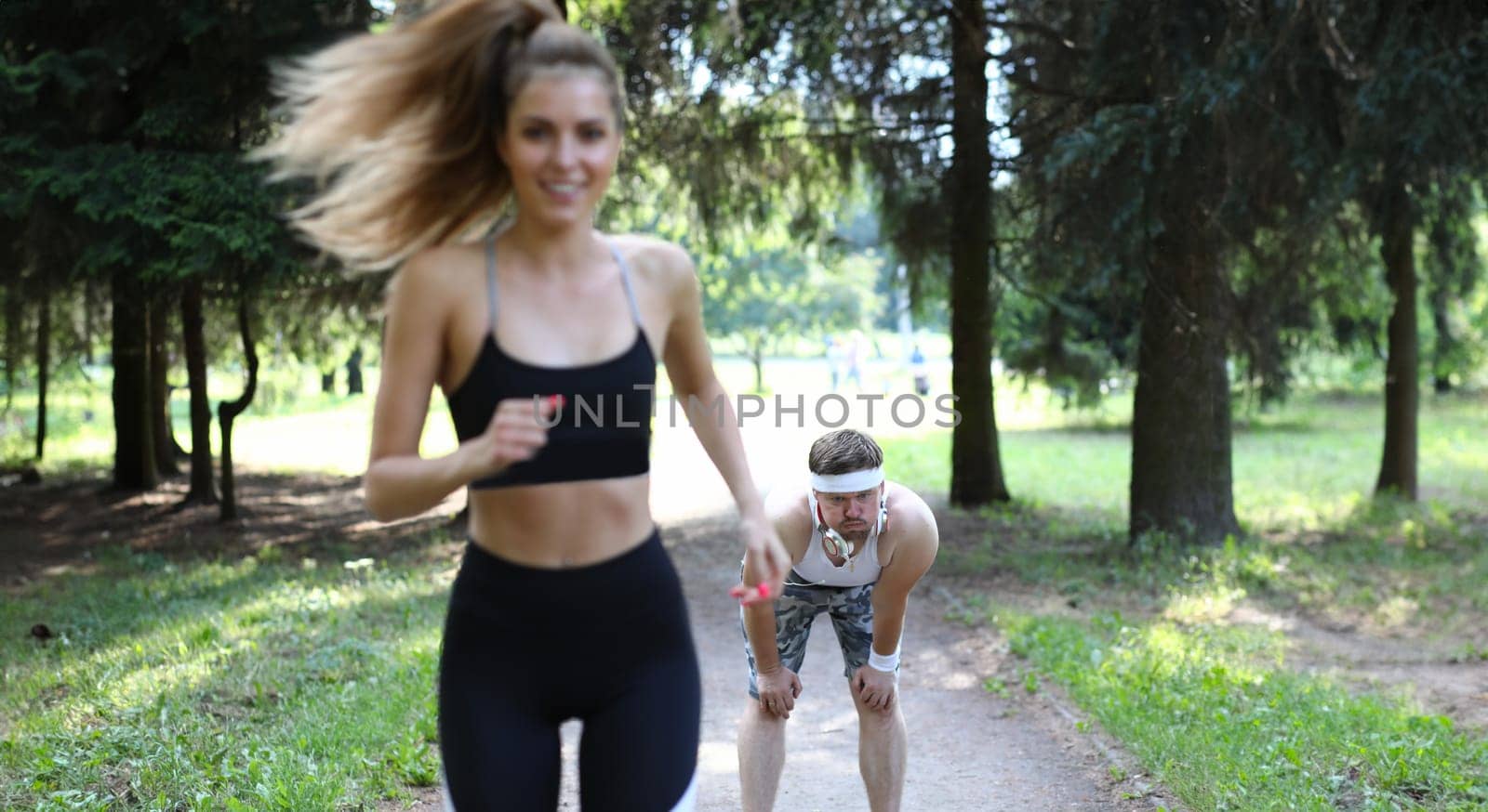 Man and woman on morning run in summer park. Cardio training is aimed at strengthening heart and increasing stamina. Motivation for morning run to tighten the body. Positive emotions from sports.