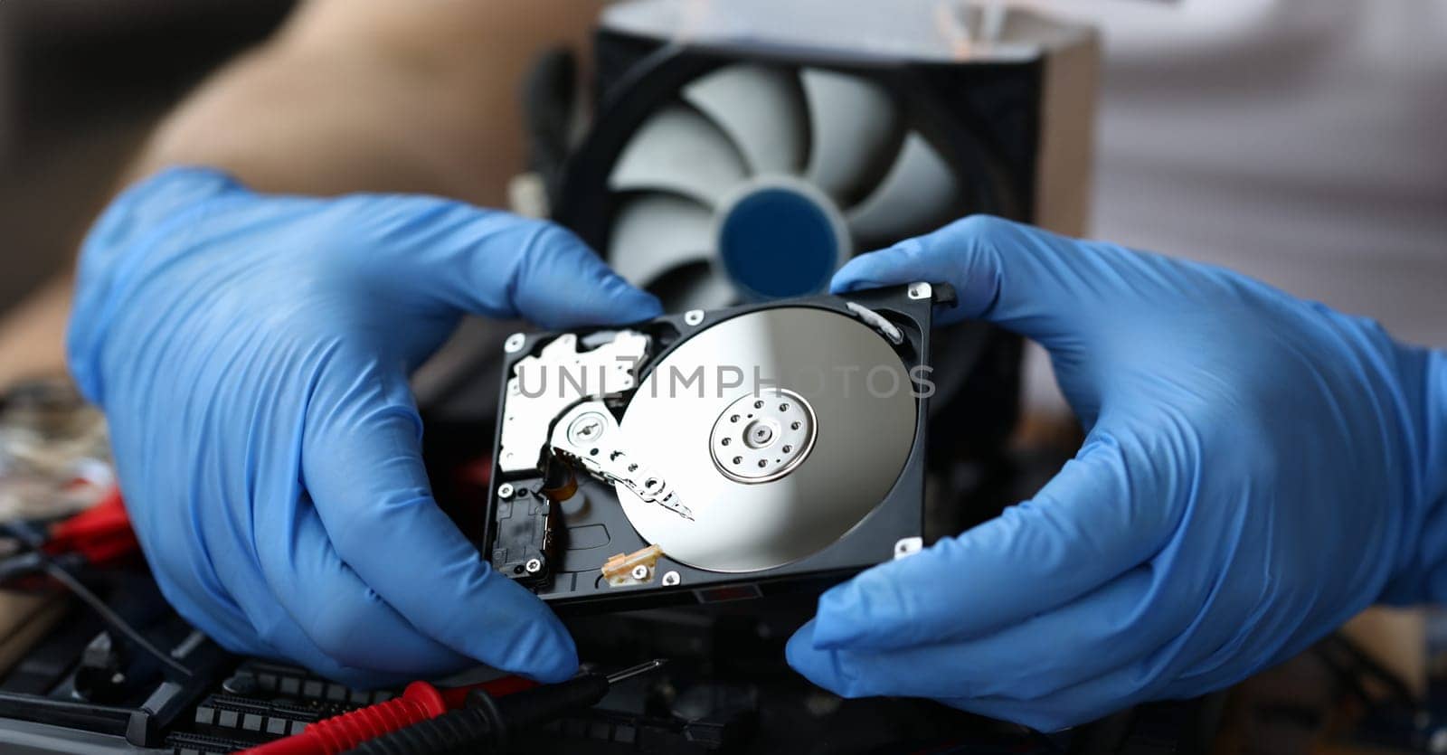 Hdd pc repair service concept. Male hand in blue protective gloves hold silver hdd and install pc hardware closeup