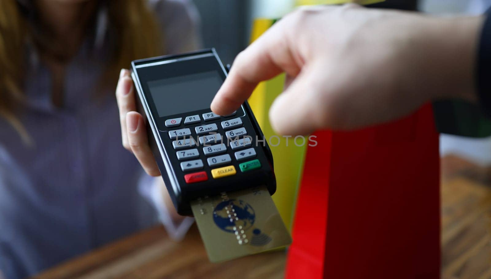 Male hand cuonter push button on modern POS terminal against shop background. Fast payment concept.