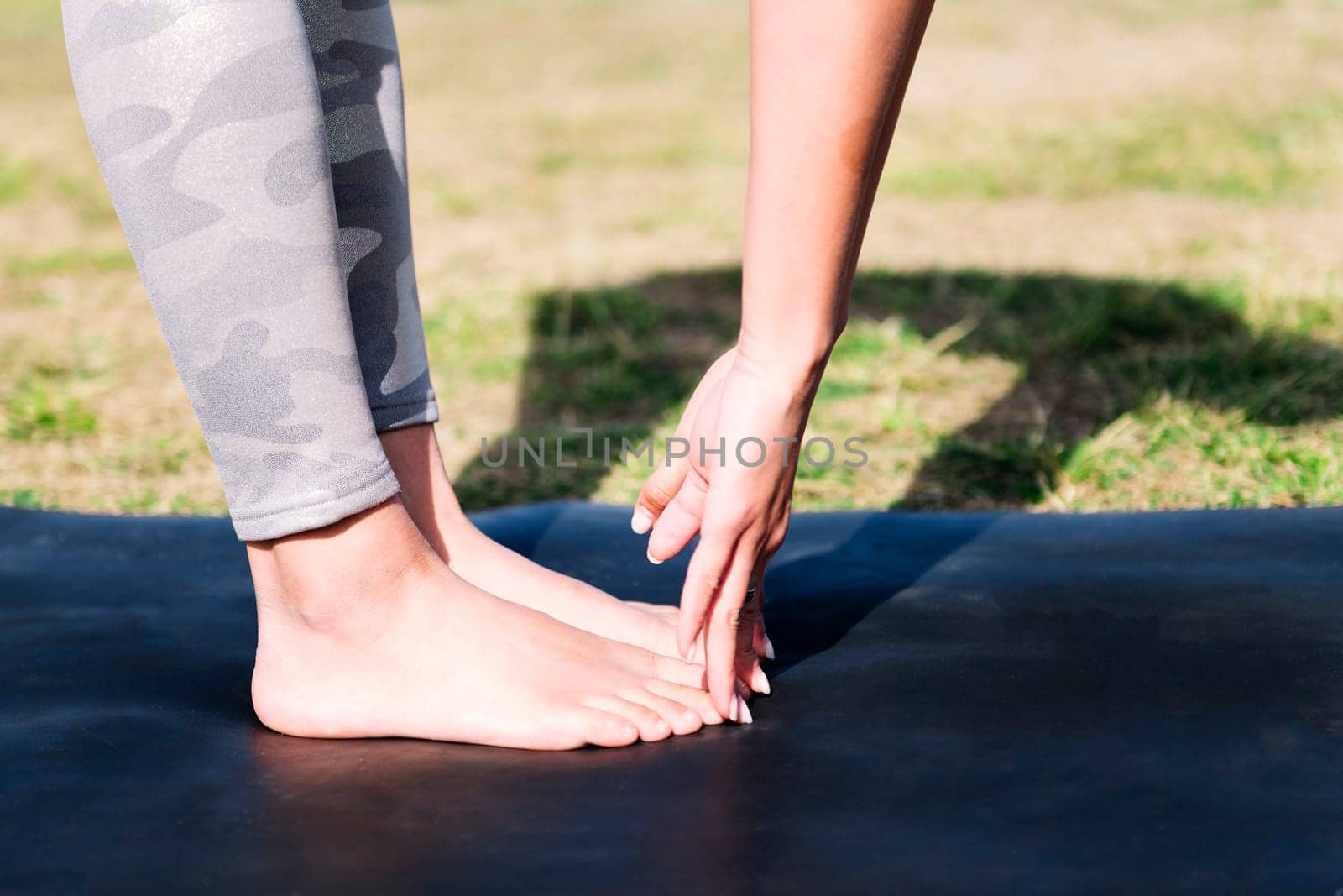 close up detail of hands and feet of a young woman doing stretches on a yoga mat, sport and active lifestyle concept