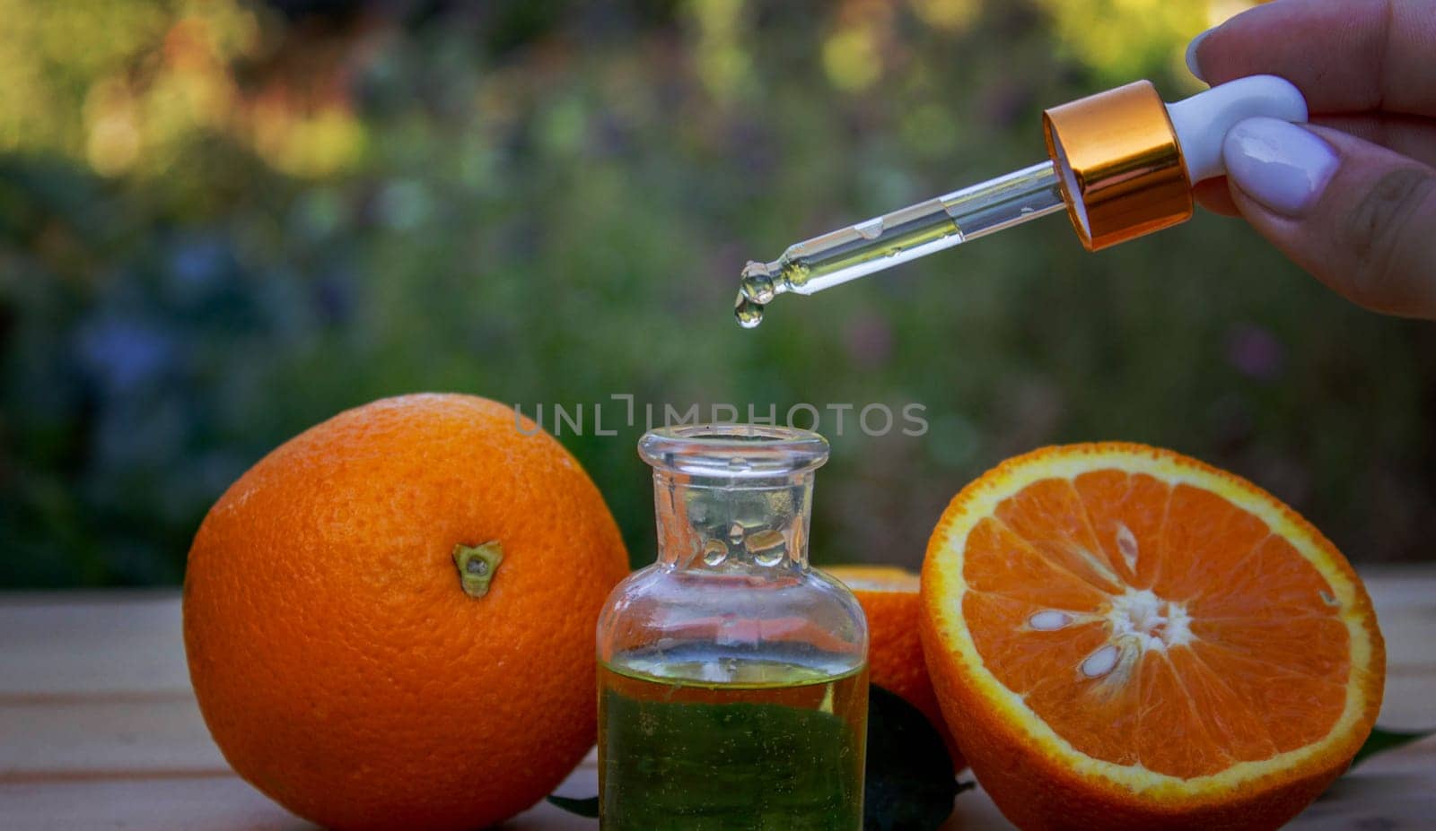 bottle of aromatic essence and fresh orange on the background of nature