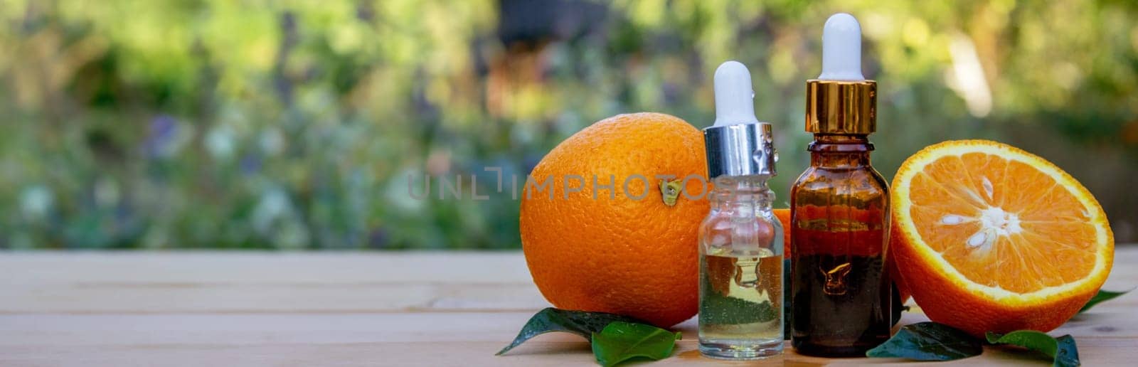 bottle of aromatic essence and fresh orange on the background of nature. by Anuta23