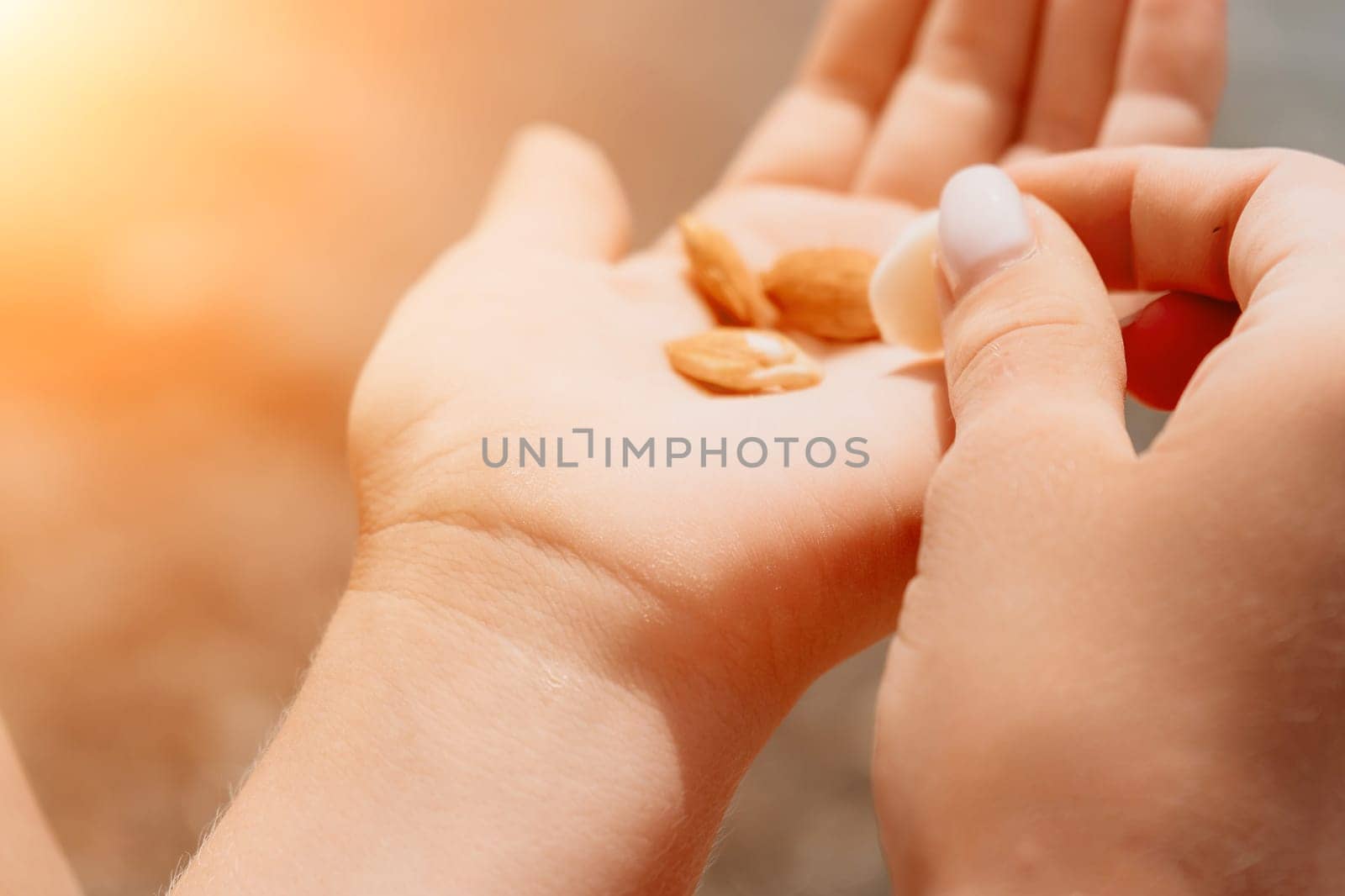 Woman eating milky almond nuts. A young caucasian woman chopping fresh green almond after morning fitness yoga near sea. Only hands are visibly. Healthy vegan food. Slow motion. Close up by panophotograph