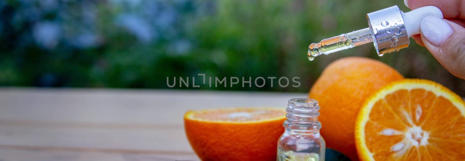 bottle of aromatic essence and fresh orange on the background of nature. by Anuta23