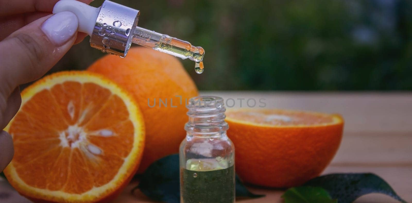 bottle of aromatic essence and fresh orange on the background of nature