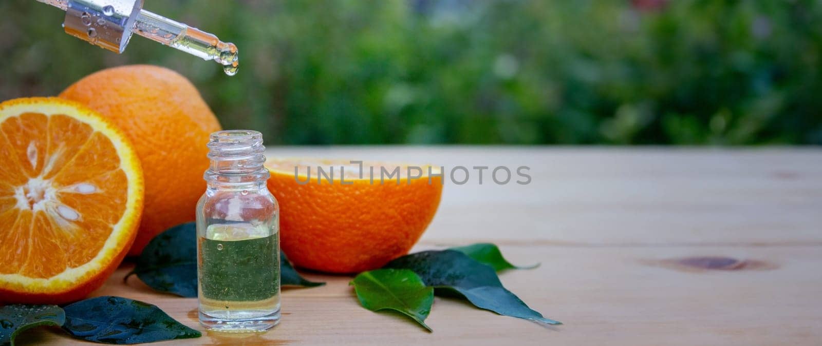 bottle of aromatic essence and fresh orange on the background of nature