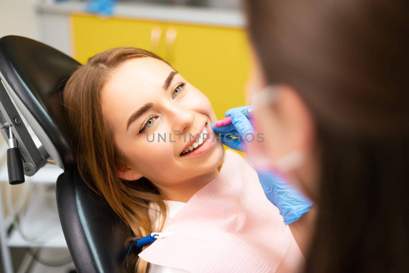 Dentist uses interdental brush for perfect clean teeth at clinic to young woman by vladimka