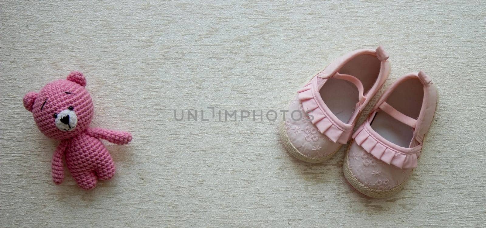 Children's shoes and teddy bear on a light background. Background with place for text.