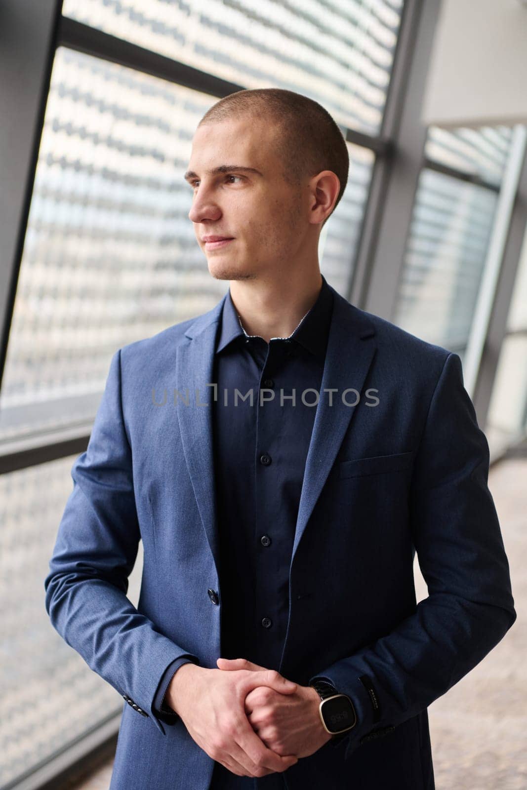 A young businessman exudes confidence and authority as he standing in the heart of his bustling factory, symbolizing leadership and success in the industrial world