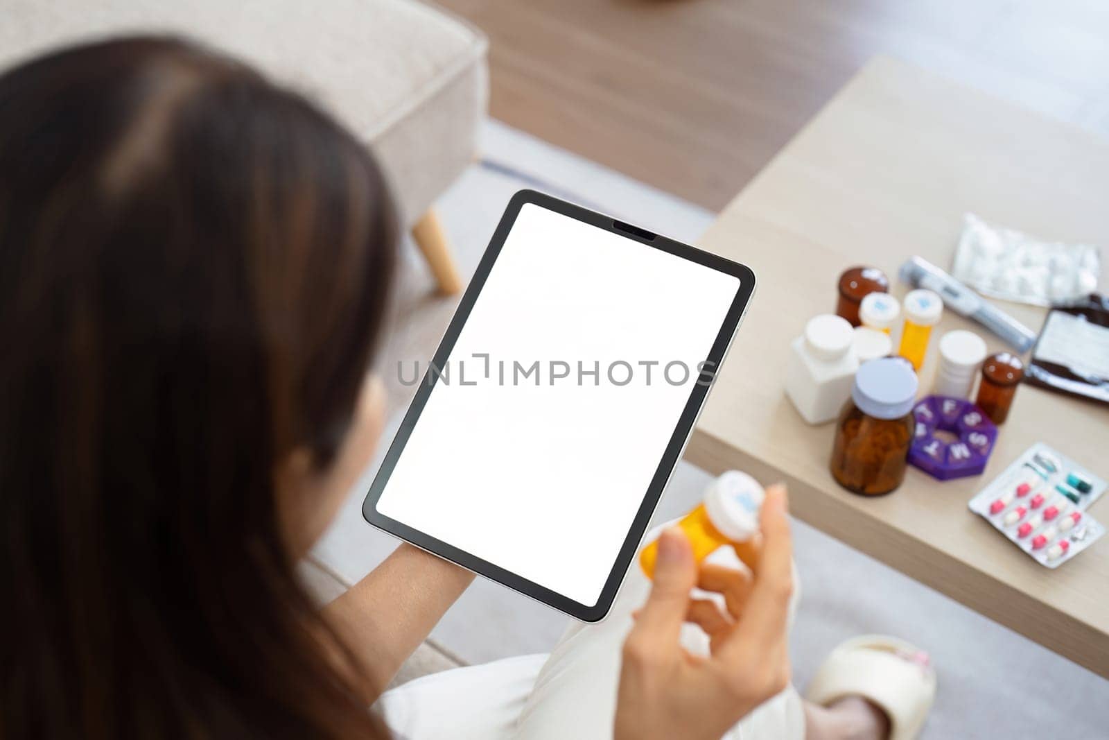senior woman examining medication next to tablet with blank screen. Home healthcare and telehealth concept by itchaznong