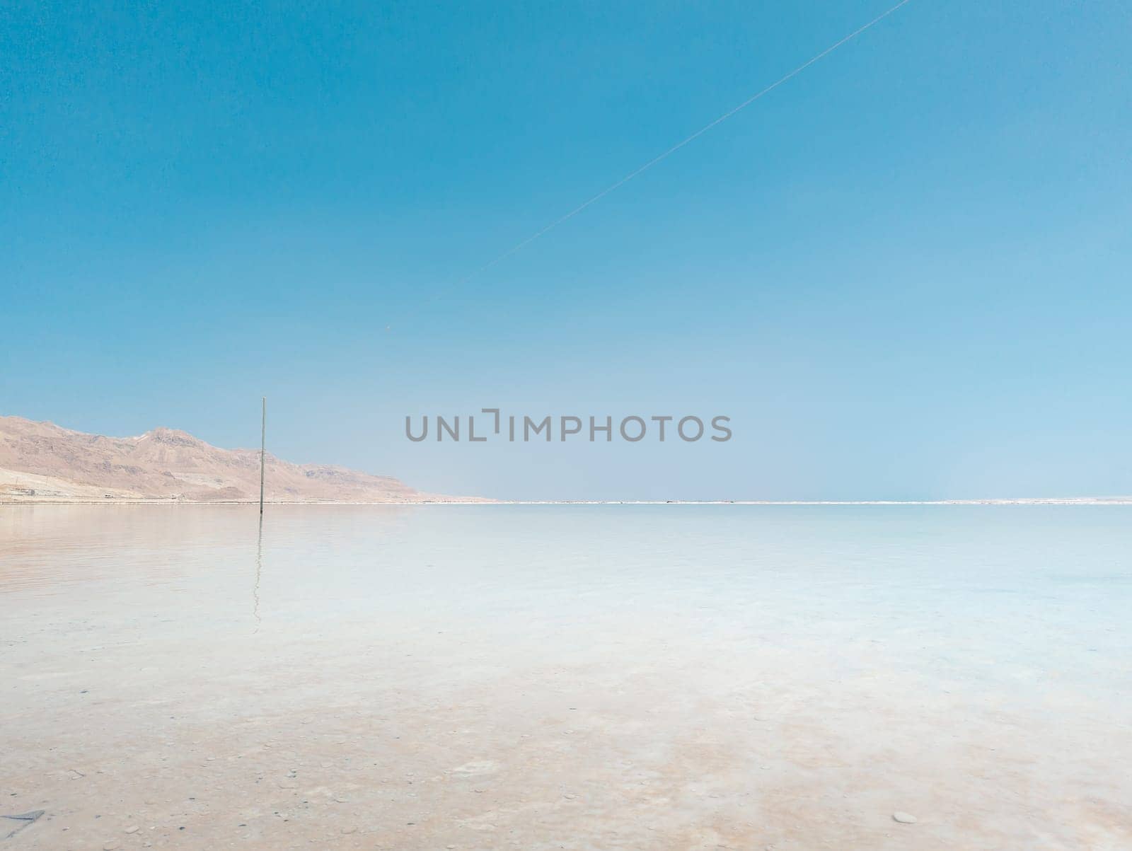 Landscape view on Dead Sea salt crystals formations, clear cyan green calm water at Ein Bokek beach, Israel