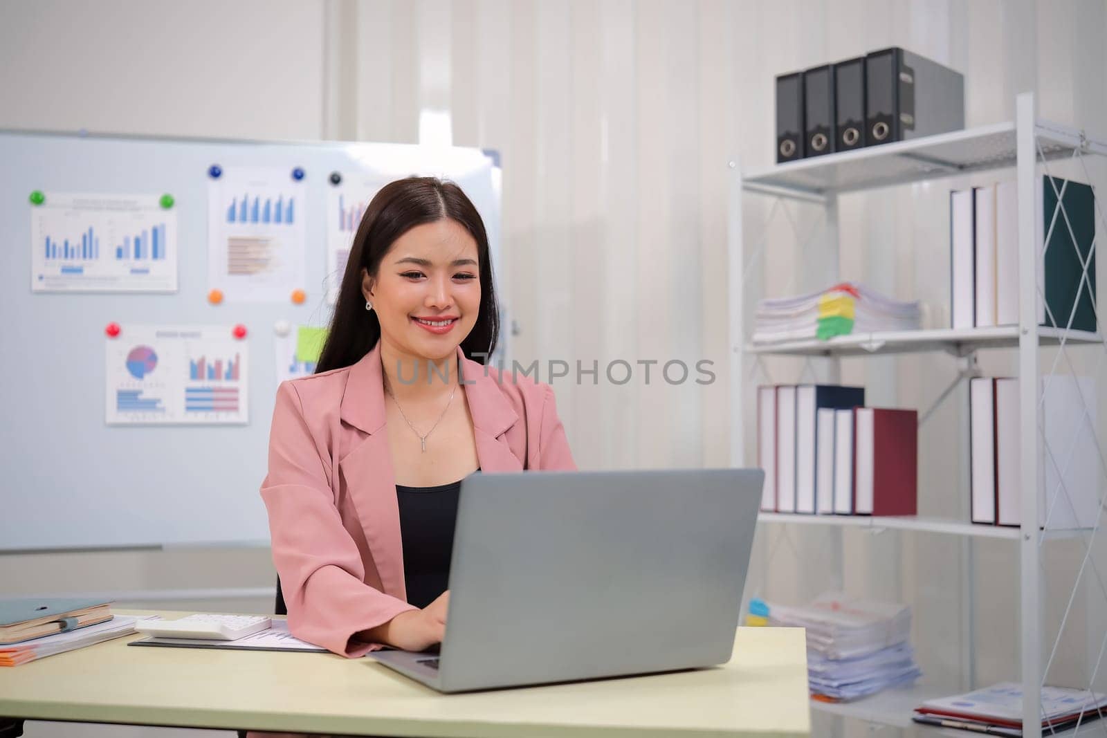 Businesswoman accountant using calculator and laptop for financial data saving in office room, Business financial, tax, accounting concept.