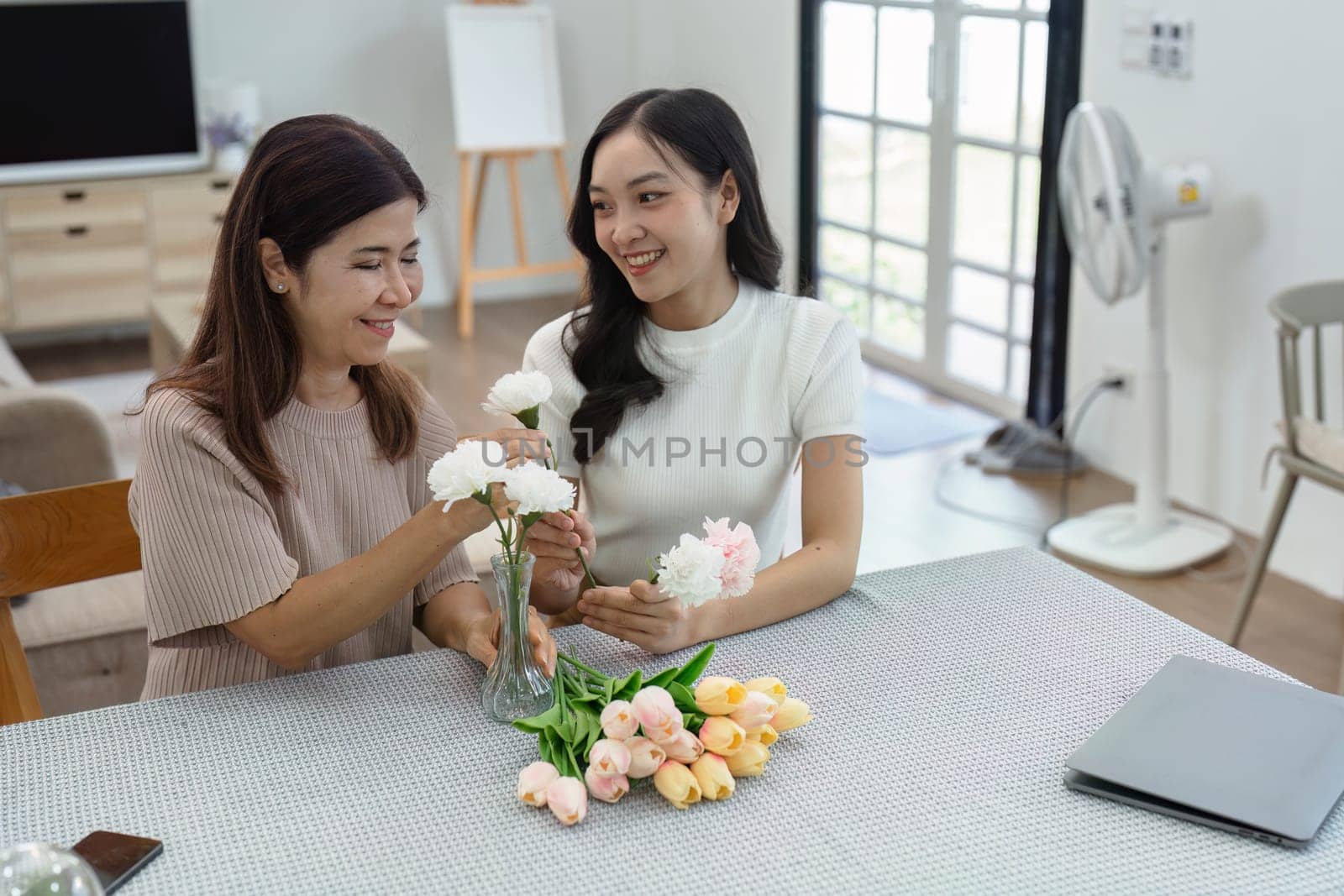 Mother and child arrange flowers together at home on the weekend, family activities, mother and daughter do activities together on Mother's Day.