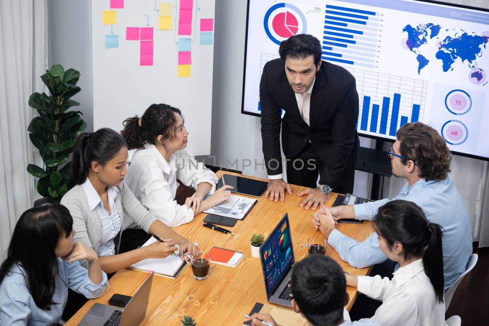 Wide top view of diverse group of business analyst team analyzing financial data report paper on meeting table. Chart and graph dashboard by business intelligence analysis. Meticulous