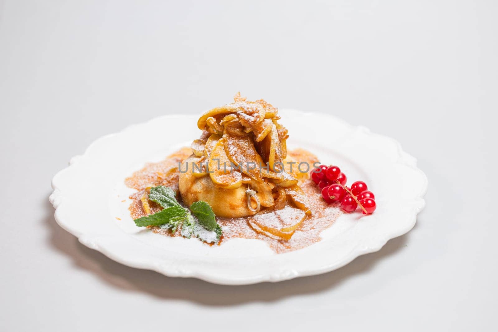 Delicate dessert of twisted dough filled with apples in caramel sauce by Pukhovskiy