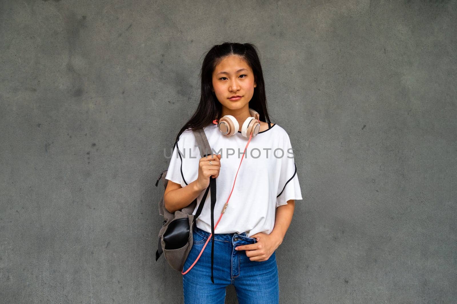 Teen Asian high school student girl standing outdoors looking at camera. by Hoverstock