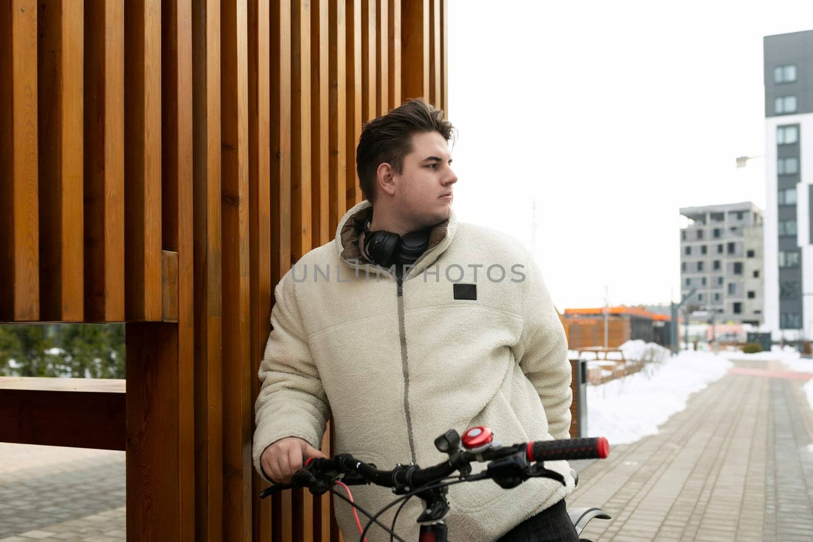 A young European man dressed in a winter jacket rented a bicycle for the weekend.