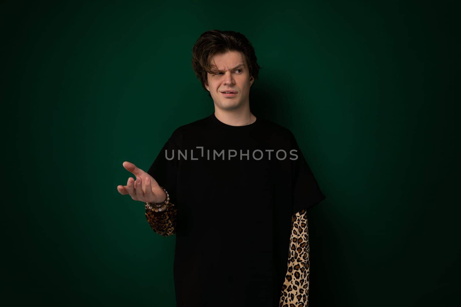 A man wearing a black shirt is standing with his hands outstretched in front of him. The background is simple and unobtrusive, allowing the viewer to focus on the mans gesture.