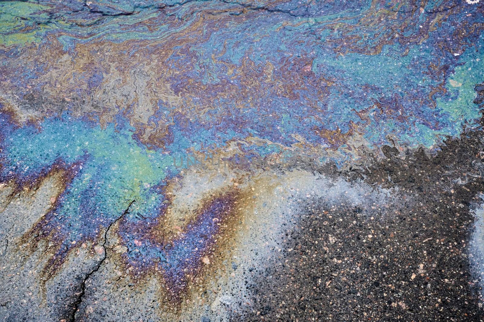 Marble spills on the water from stains of gasoline and oil. Abstract background from motor oil, gas or petrol spilled on asphalt