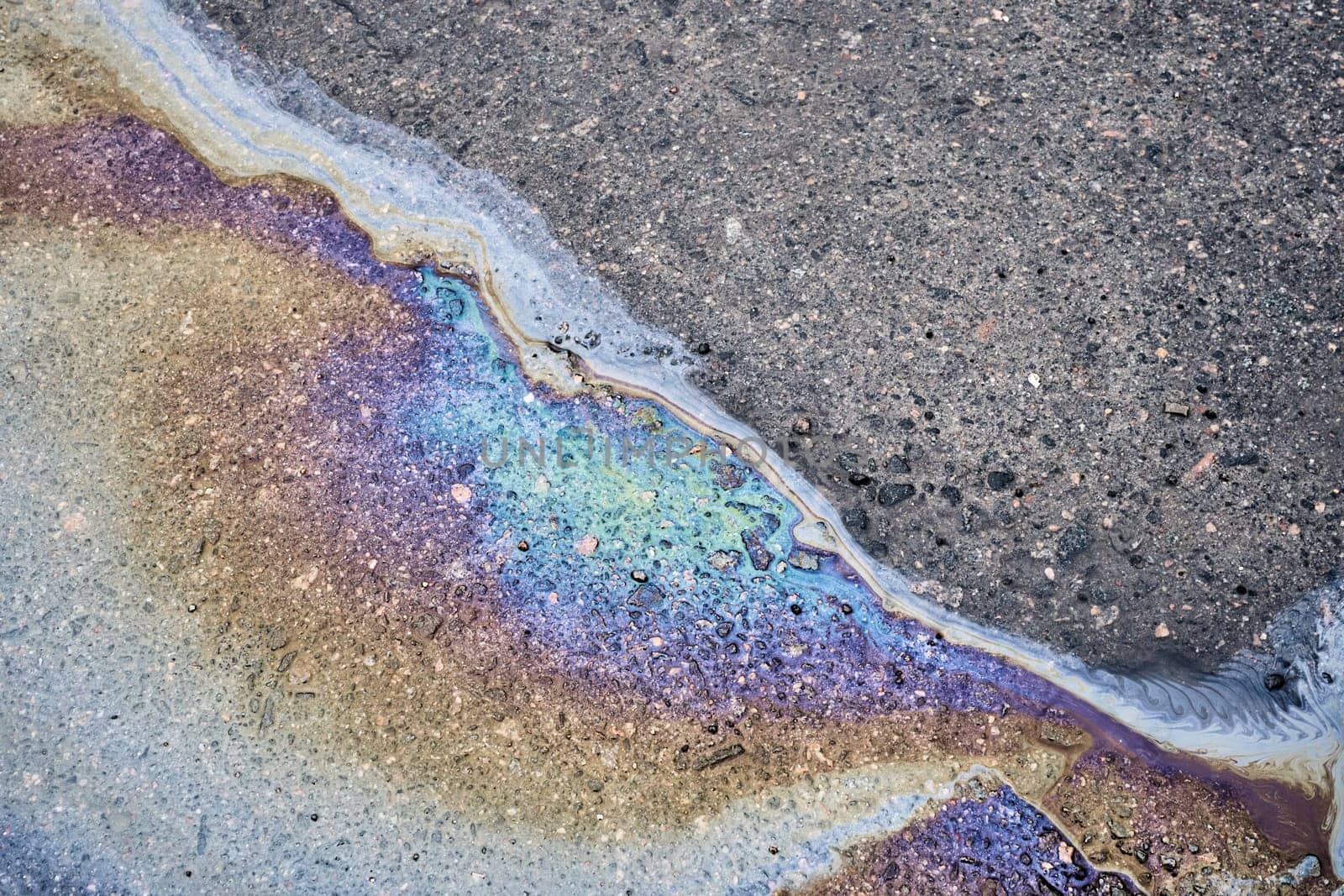 Color gasoline fuel spot on black asphalt, industrial pollution concept