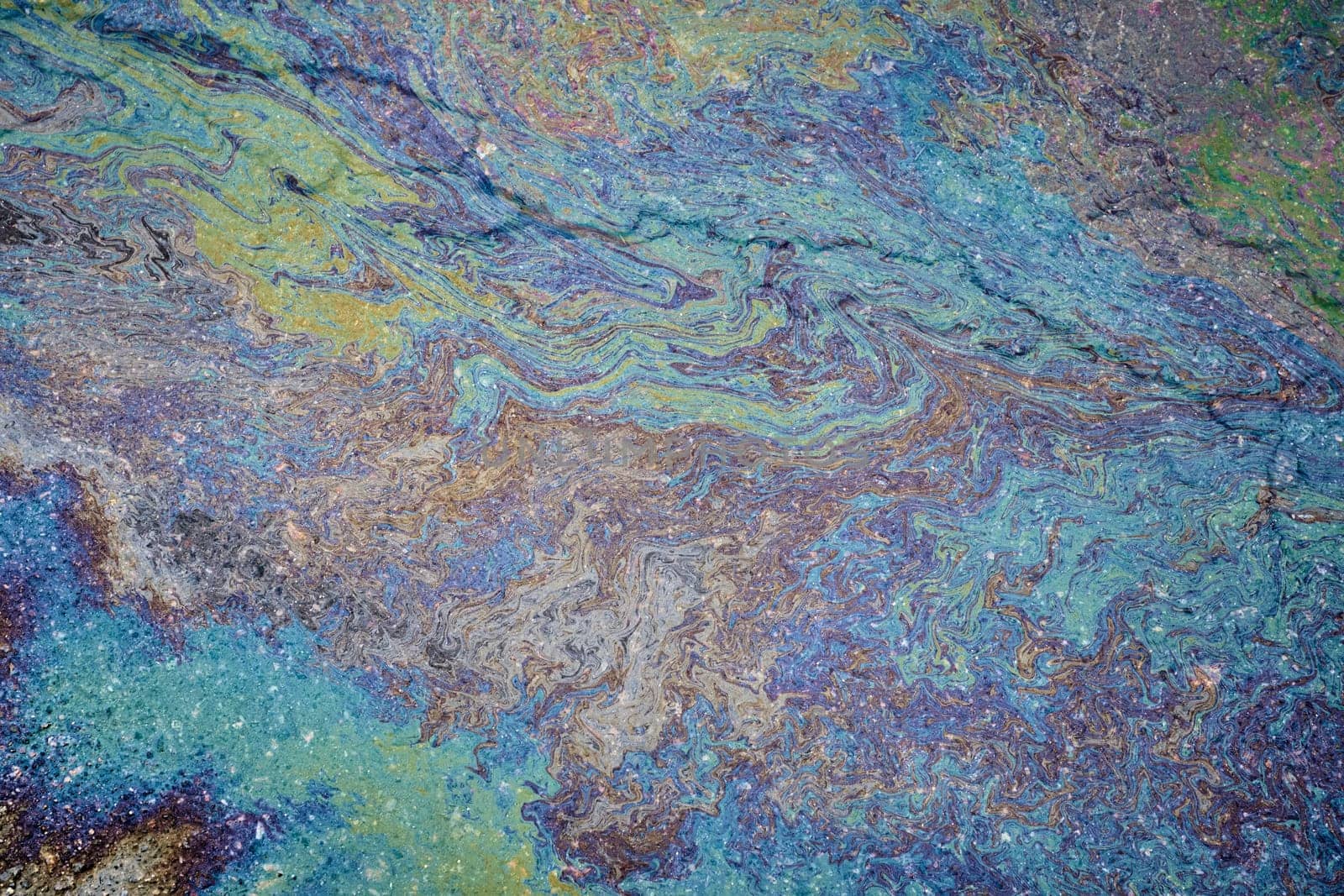 Marble spills on water from gasoline and oil stains. Abstract background from spilled motor oil, gas or gasoline on the asphalt.