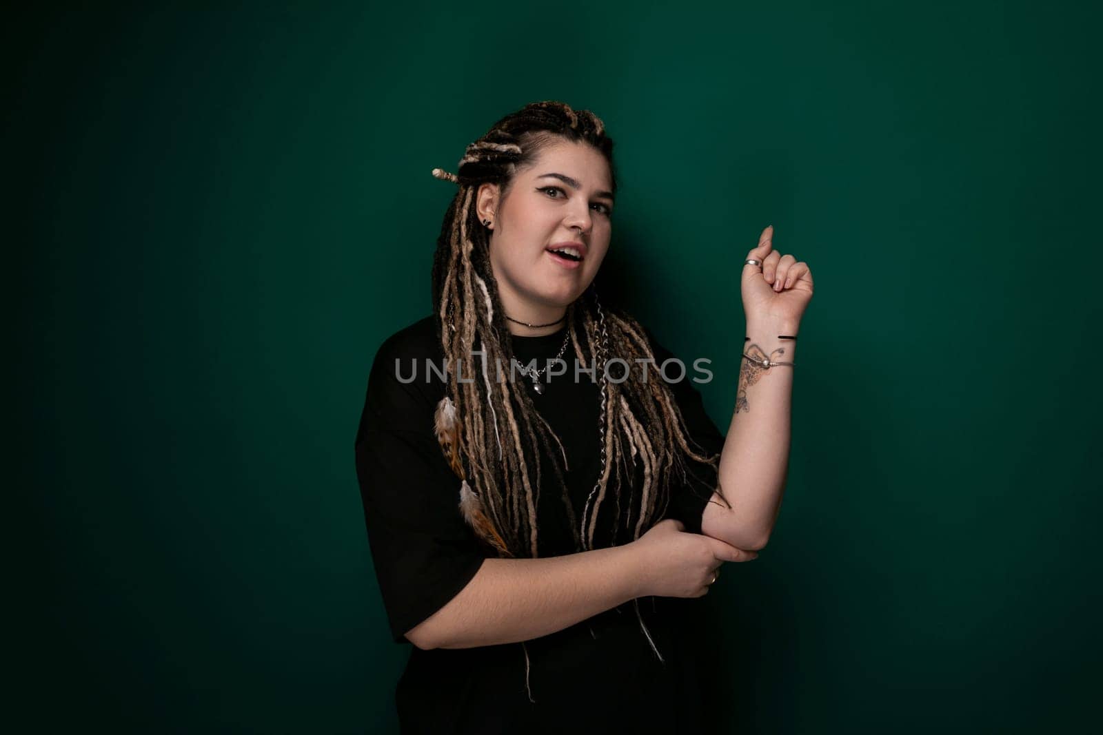 A woman with dreadlocks is pointing emphatically at an unseen object or direction, her facial expression indicating urgency or excitement. She is wearing a casual outfit and appears engaged in the moment.