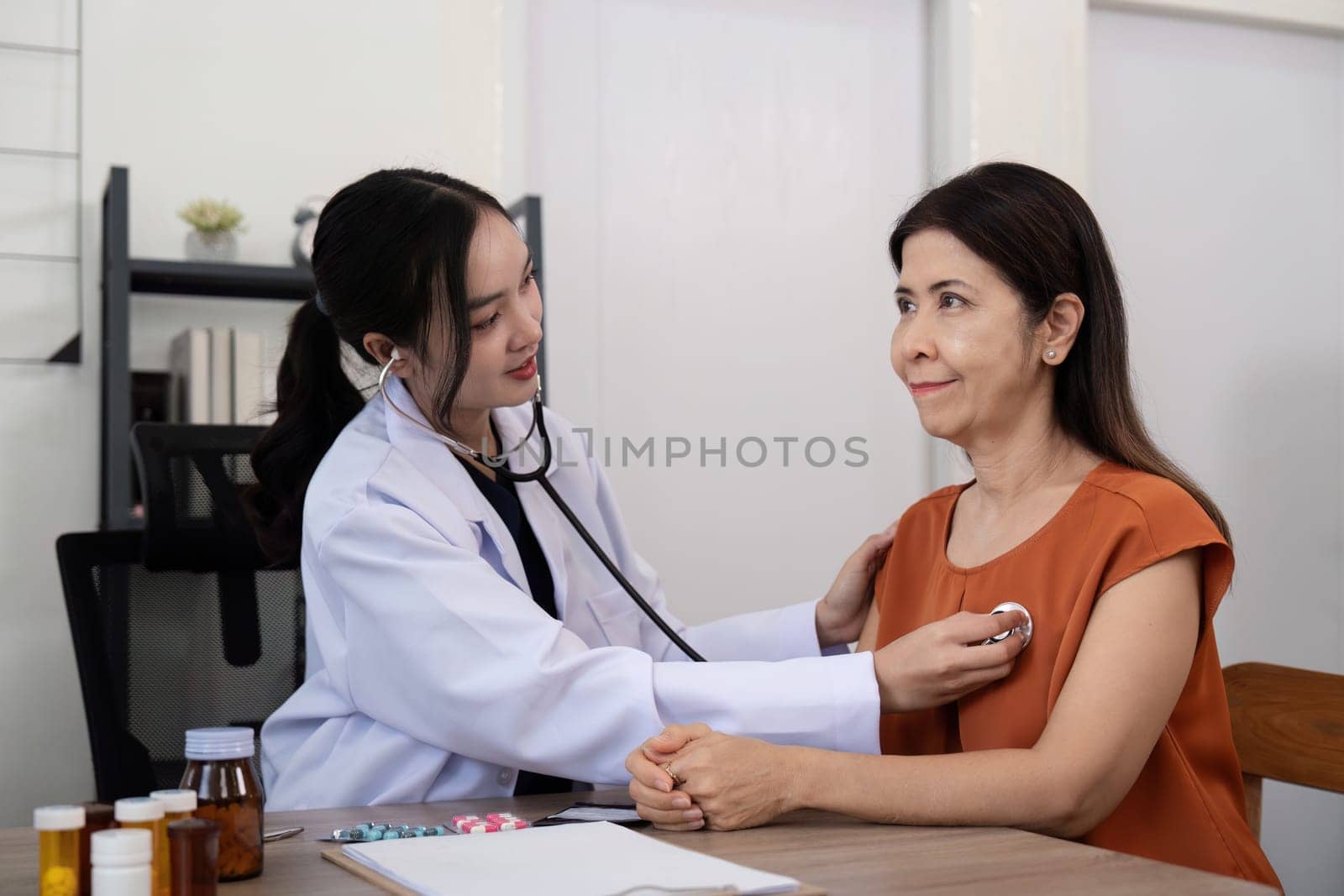 Elderly woman asian patient are check up health while a woman doctor use a stethoscope to hear heart rate. elderly healthcare concept.