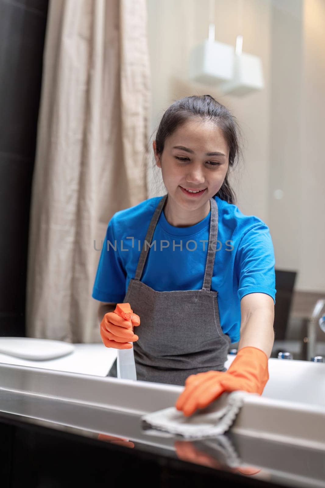 Professional cleaning service company employee in rubber gloves cleaning and detergent spray in bathroom by nateemee