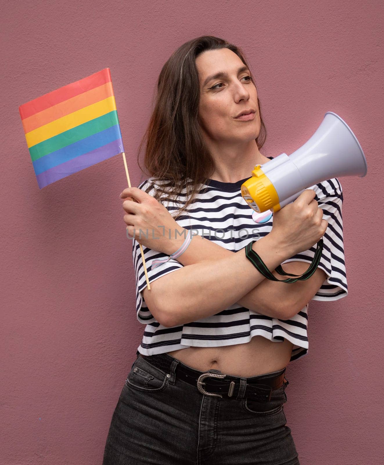 Transsexual woman looking away and holding a rainbow flag and a megaphone to support LGBTQ community as activist by papatonic