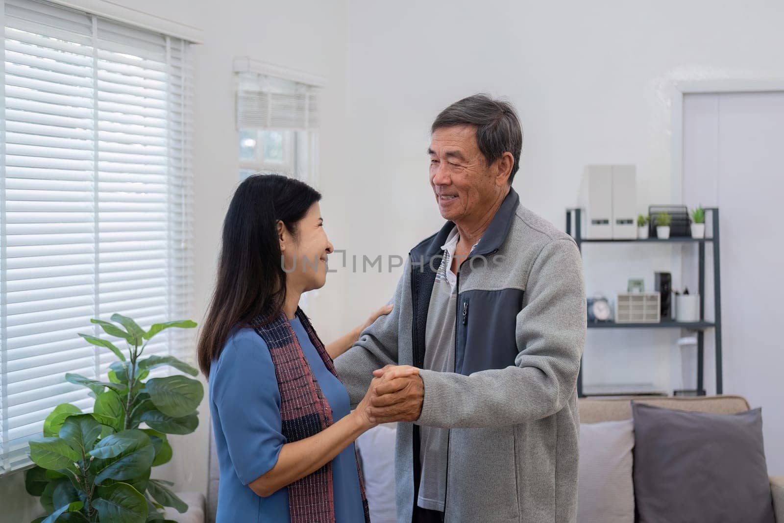 An elderly couple in their 60s happy danced together in the living room..