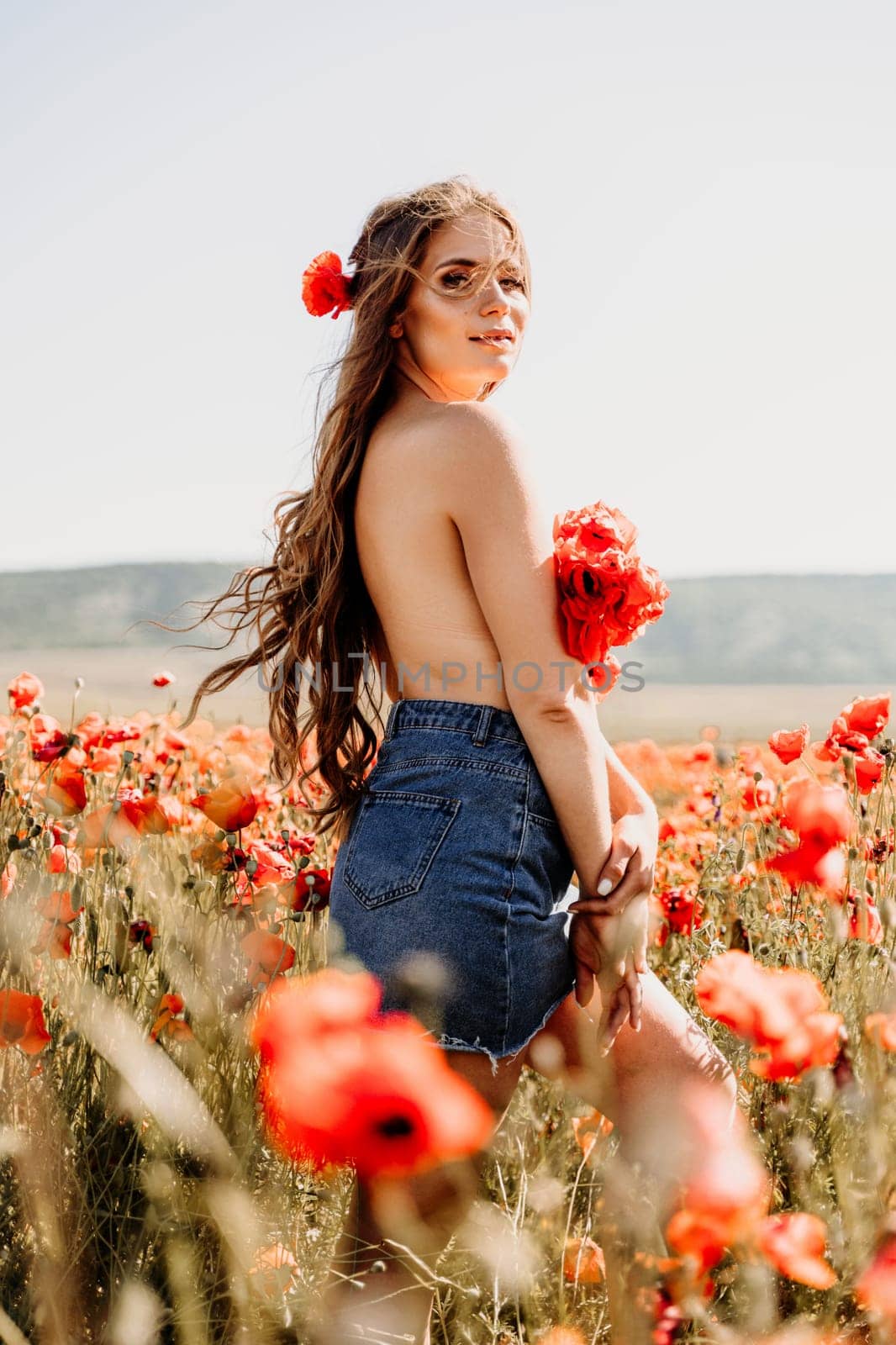 Woman poppies field. portrait of a happy woman with long hair in a poppy field and enjoying the beauty of nature in a warm summer day